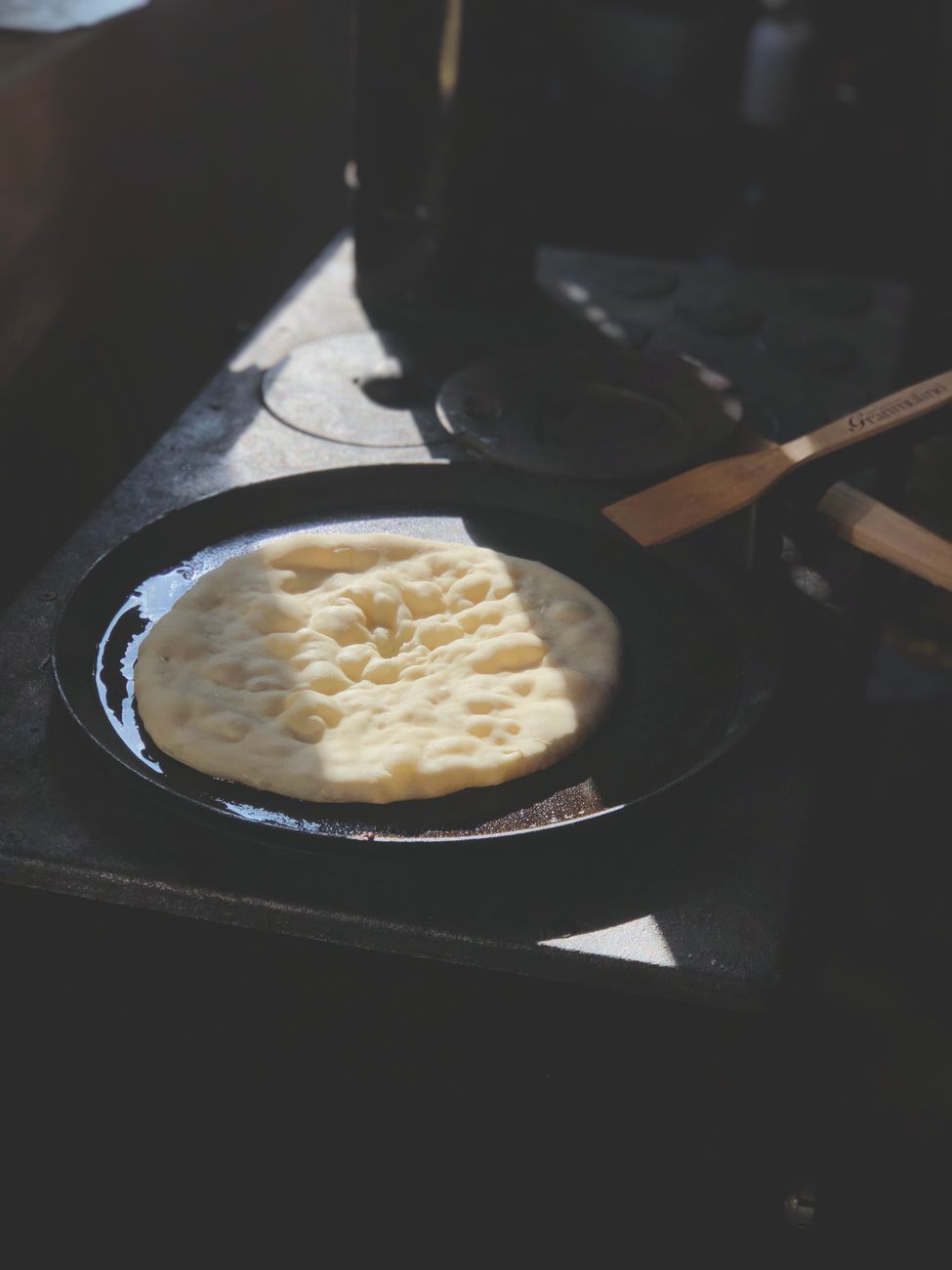 Homemade flatbread cooking on a cast iron skillet in a warm rustic kitchen — the daily use that builds seasoning over months.