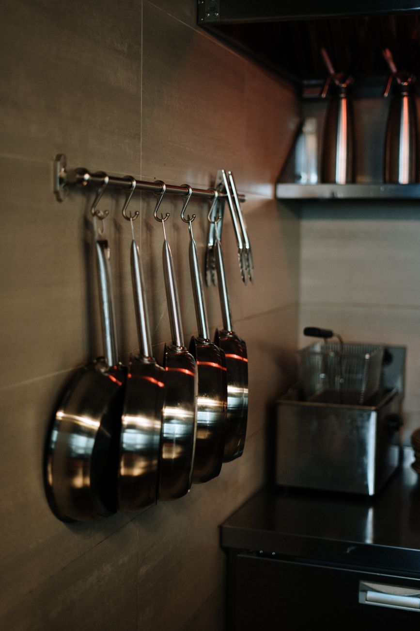 A row of stainless steel pans hanging in a contemporary kitchen — the coating-free category, where the substrate itself does the work.