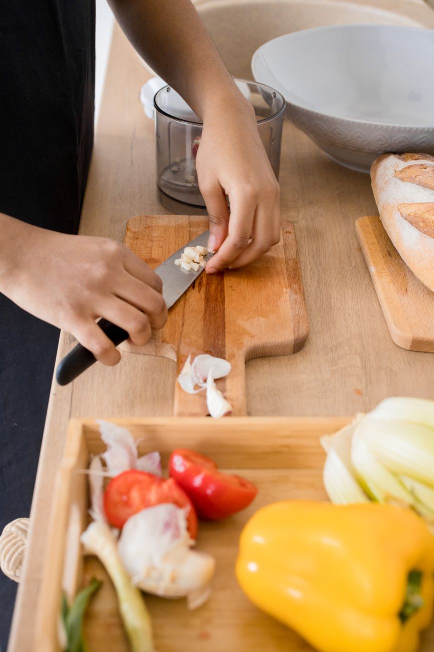Hands slicing garlic and vegetables on a wooden board — the working-week technique the Fibrox was made for.