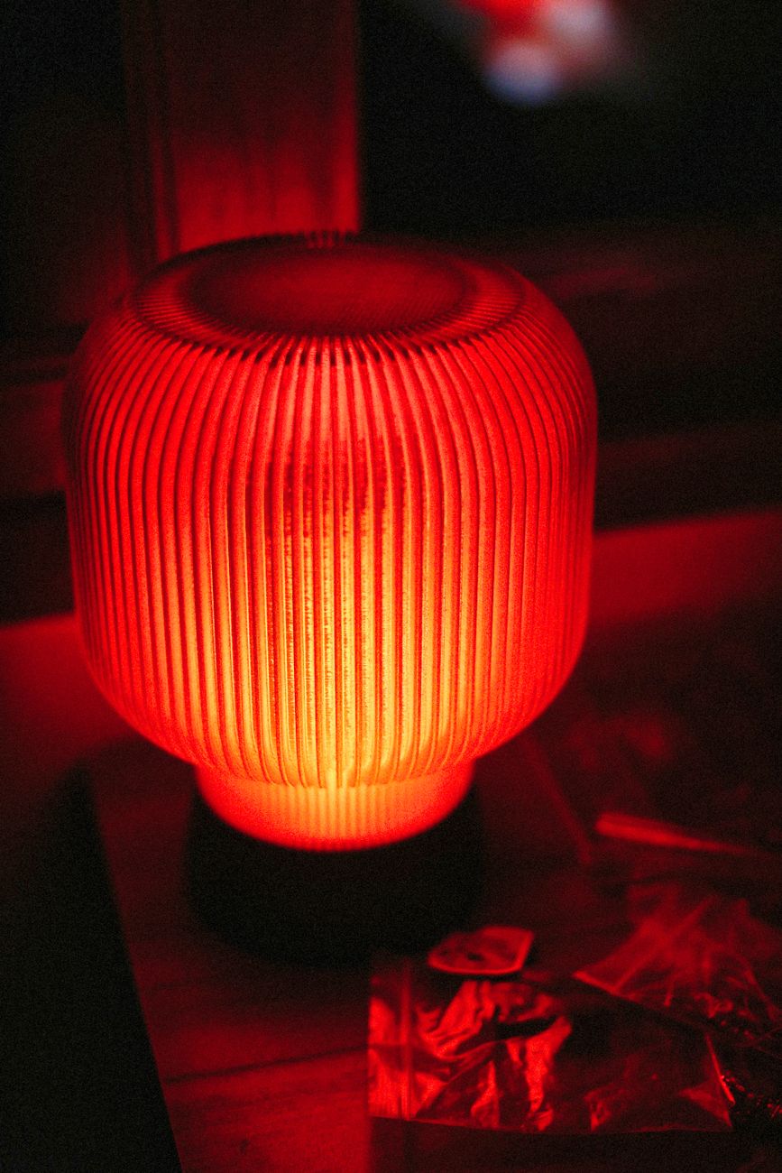 A single warm-bulb table lamp casting a focused pool of amber light in an otherwise dim room — the geometry the four-metric rule is built around.