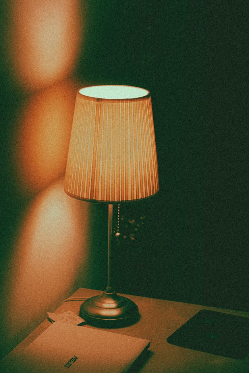 A glowing lamp on a desk seen from above at dusk — the heirloom fixture at end of day.