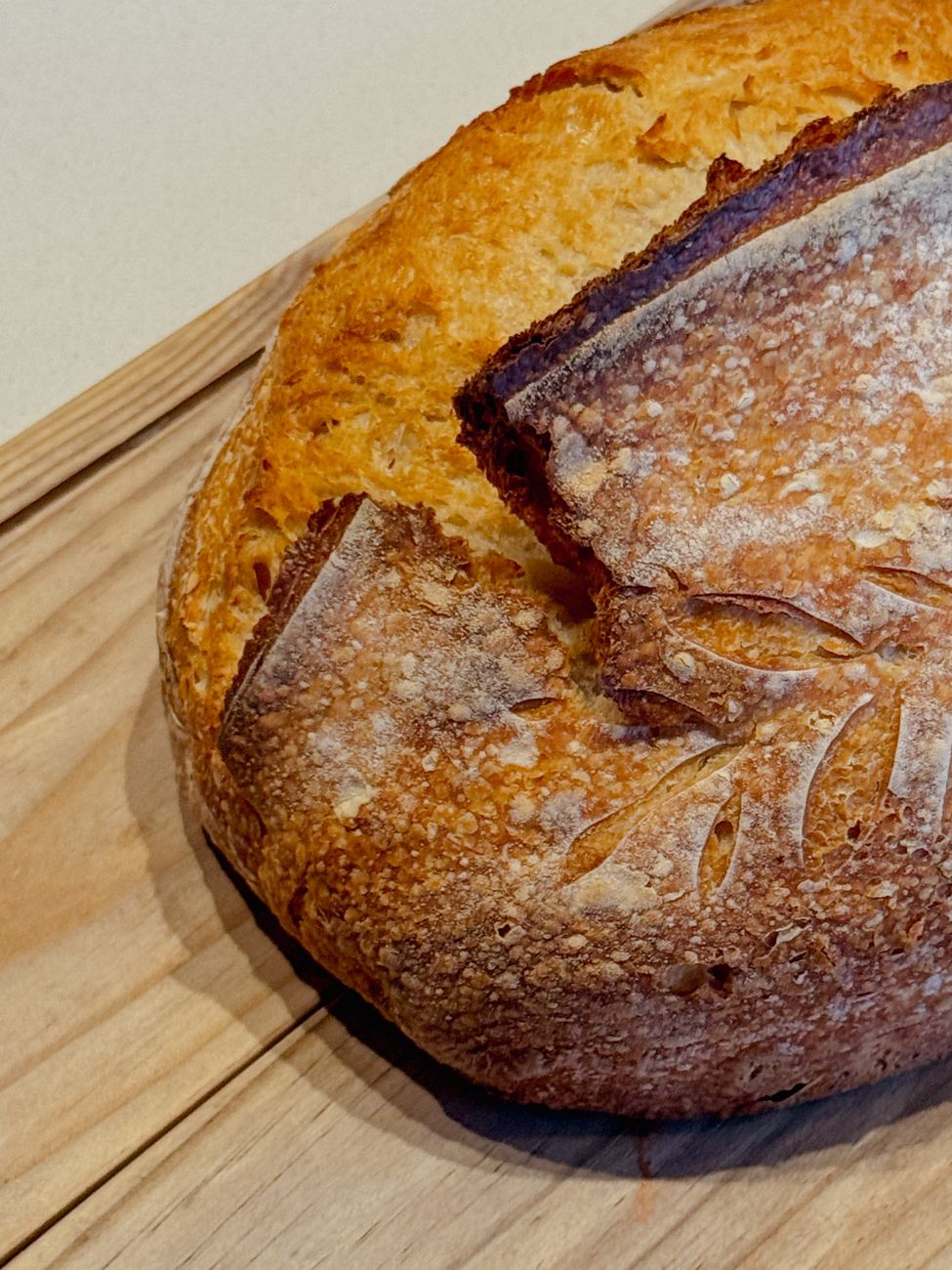 A round sourdough loaf on a wooden board with a dark crust — baked in a Dutch oven, the heirloom use case.
